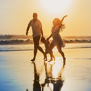 family running on beach at sunset