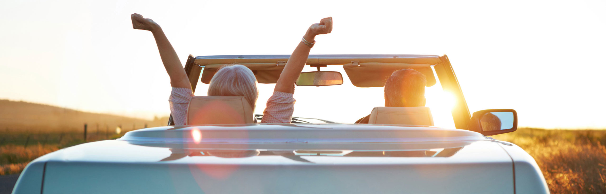 couple sitting in parked convertible