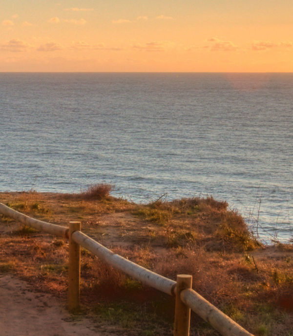 view of hiking trail with ocean in background at sunset