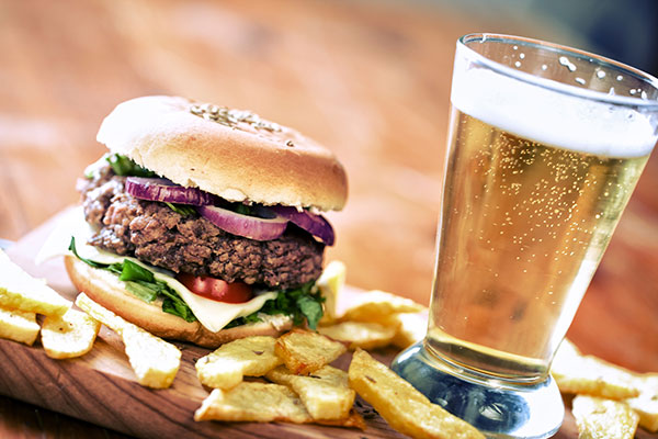 wooden board with cheeseburger, french fries and a glass of beer