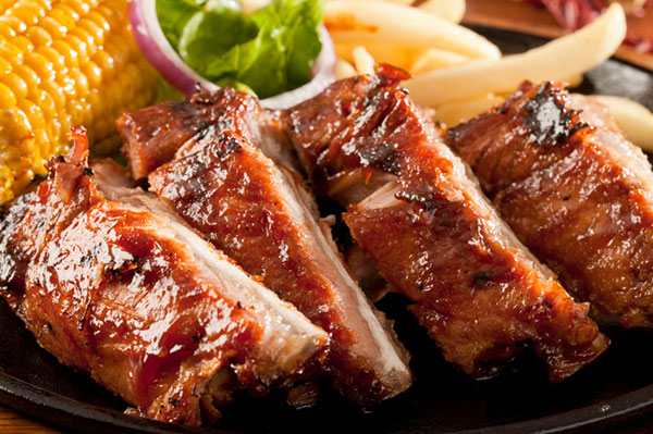 plate of barbecue ribs with a side of corn and french fries