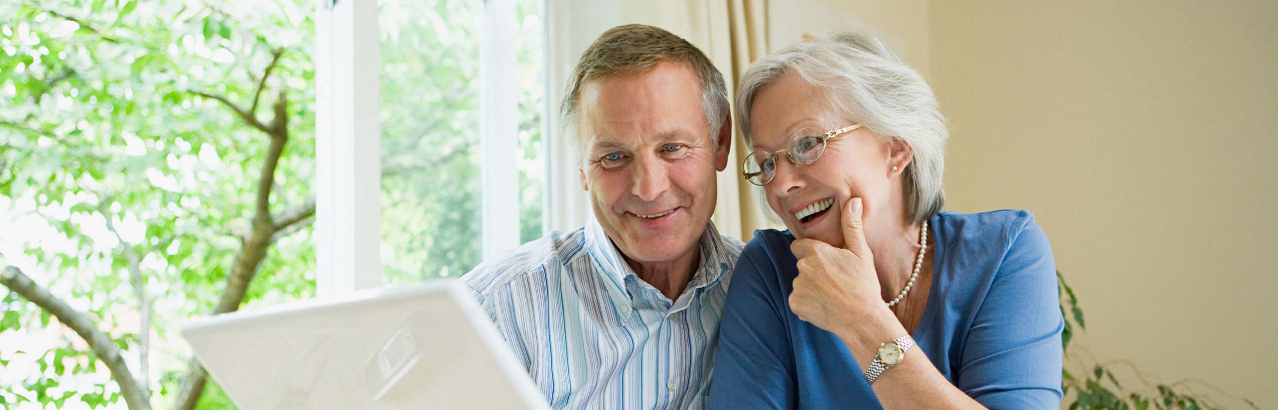 older couple looking at computer and travel guide books
