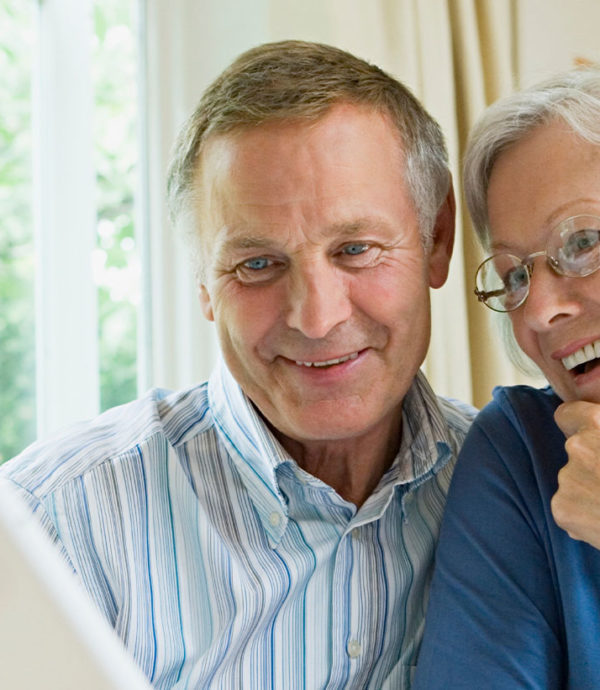 older couple looking at computer and travel guide books